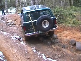 1979 Ford Bronco - A green Ford Bronco navigates a challenging off-road trail, demonstrating its capabilities on rough terrain.