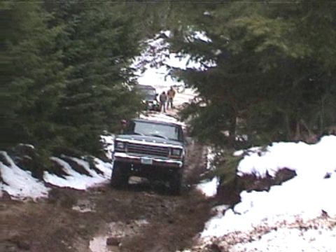 1979 Ford Bronco - A 1979 Ford Bronco navigates a challenging off-road path with snow and mud.