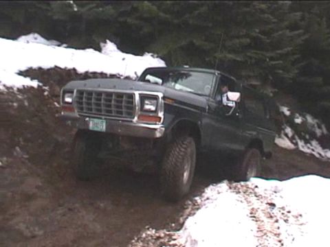 1979 Ford Bronco - A Ford Bronco navigates a challenging off-road path with snow and mud.
