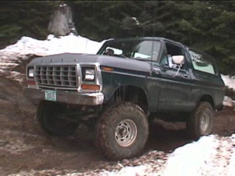 1979 Ford Bronco - A lifted 1978 Ford Bronco navigates a challenging off-road path with snow and mud.