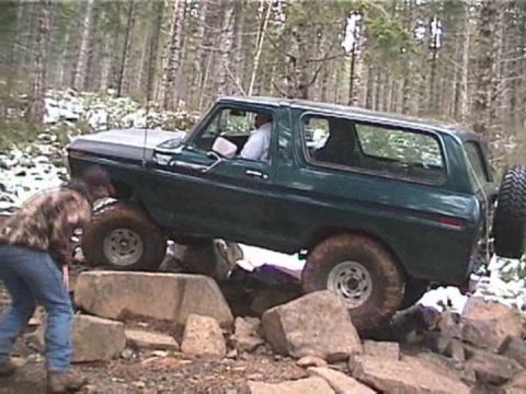 1979 Ford Bronco - Ford Bronco is shown off-roading over large rocks in a wooded area.