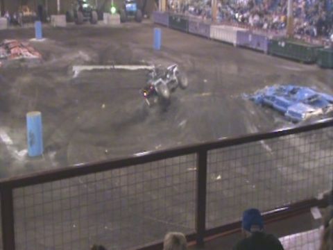 1984 Ford Bronco - A monster truck is captured mid-air during a performance in an indoor arena.