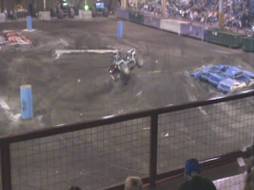 Monster truck doing a stunt in an arena with spectators in the background