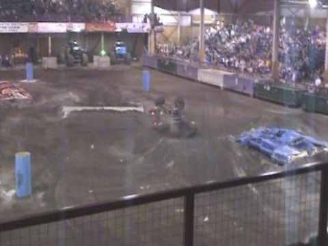 1984 Ford Bronco - Monster trucks are performing in an arena with a crowd watching the event.