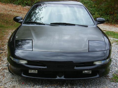 1995 Ford Probe - Front view of a black car with pop-up headlights and a matte grey hood.