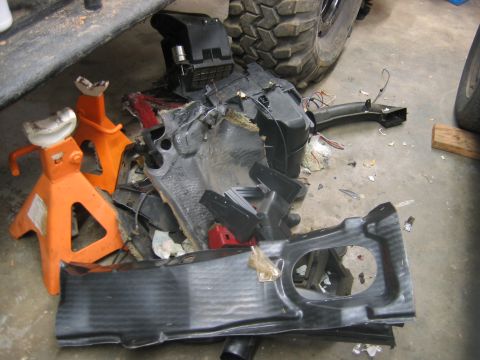 1992 Ford Mustang - Disassembled vehicle interior components are piled on the floor, supported by jack stands.