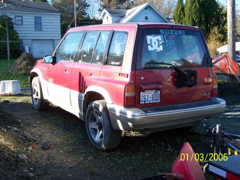 1988 Suzuki Samurai - This red and white SUV is seen from the rear, a SUZUKI decal and a DC Shoes logo on the back window.