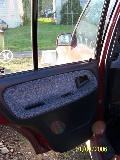 1988 Suzuki Samurai - The interior door panel and side mirror are visible in this photo of a red vehicle.