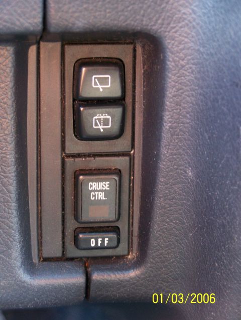 1988 Suzuki Samurai - Close-up of dashboard controls, including cruise control and wiper settings, on a blue textured surface.