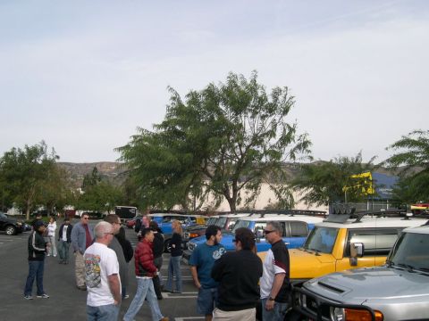 2007 Toyota FJ Cruiser - A group of Toyota FJ Cruisers, including a yellow one, are parked in a lot while people gather around.