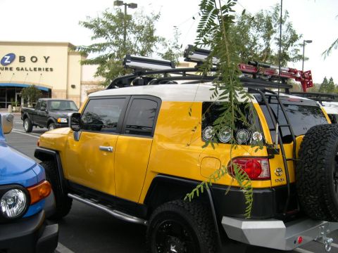 2007 Toyota FJ Cruiser - A yellow and white 2007 Toyota FJ Cruiser is parked next to a blue vehicle, with a black pickup truck in the background.
