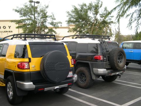 2007 Toyota FJ Cruiser - Three Toyota FJ Cruisers are parked in a lot, one yellow, one black, and one blue.