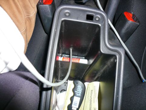 1996 Ford Probe - Center console storage area with a charging cable and various items inside.