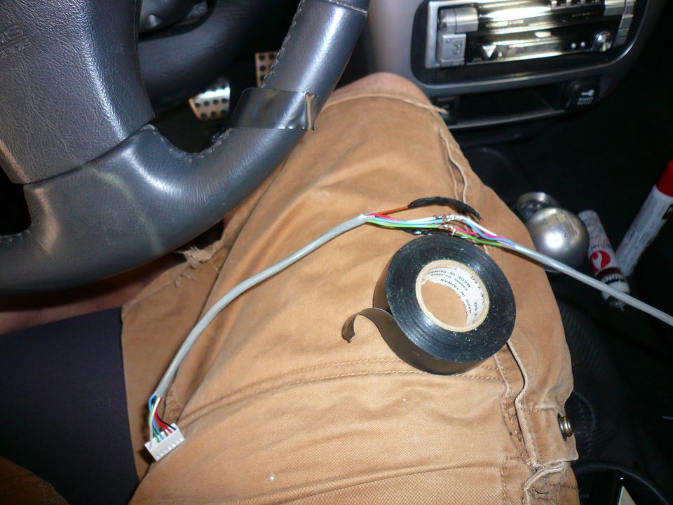 Close-up of car interior with wires being taped up near the steering wheel and gear shift
