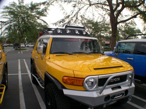 2007 Toyota FJ Cruiser - Two FJ Cruisers are parked in a lot, one yellow and one blue, with trees in the background.