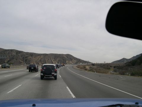 2007 Toyota FJ Cruiser - A convoy of vehicles, including a white Toyota FJ Cruiser, travels down a highway surrounded by hills.