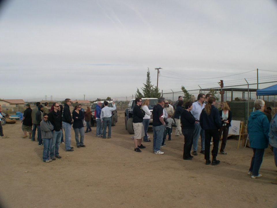 People gathered around a white 2007 Toyota FJ Cruiser and another SUV