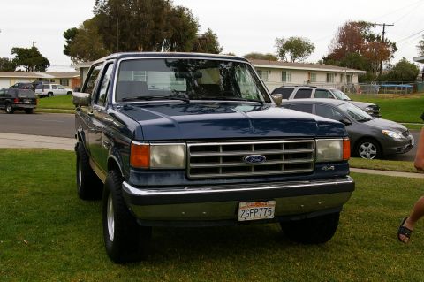 1986 Ford Bronco - The front of a blue 1986 Ford Bronco is captured in this photo, parked on a grassy lawn.