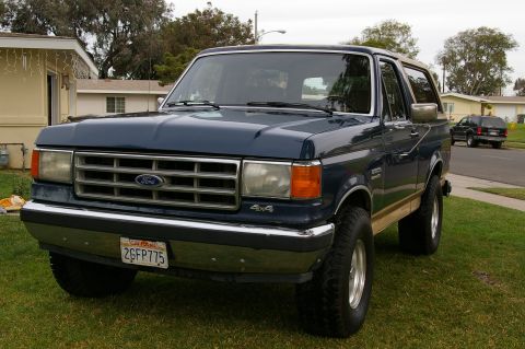 1986 Ford Bronco - This Ford Bronco features a chrome grille and 4x4 badging, with a tan lower body trim.