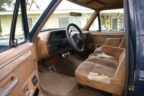1986 Ford Bronco - Interior view of a worn SUV, with tan upholstery and a dark dashboard.