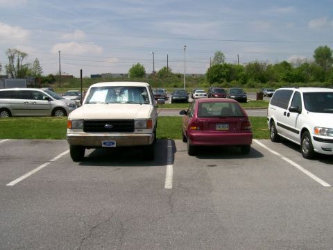 1988 Ford Bronco - White Ford F-Series truck from the late 1980s is parked in a lot.