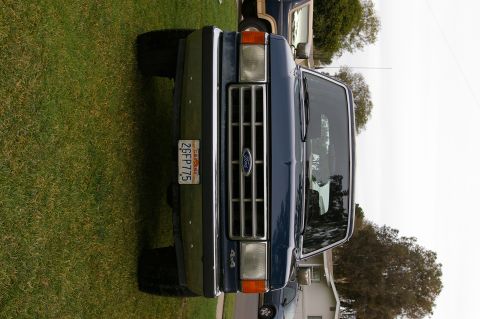 1986 Ford Bronco - Front view of a blue Ford F-Series truck with a chrome grille and a California license plate.