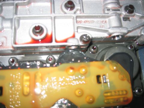 1973 Ford F-100 - Close-up view of a transmission valve body, showing red fluid and a yellow circuit board with visible components.