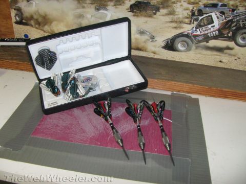 1968 Ford Mustang - A set of darts rests in an open case, with a backdrop depicting a desert off-road race.
