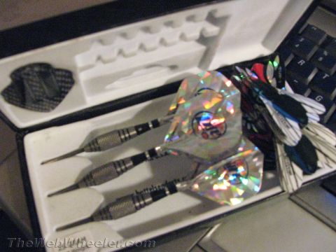 1968 Ford Mustang - A set of darts with holographic flights rests in a case, positioned near a computer keyboard.