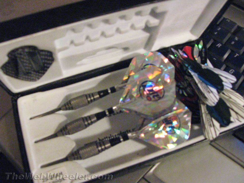 darts in a case, some with holographic flights, next to a keyboard