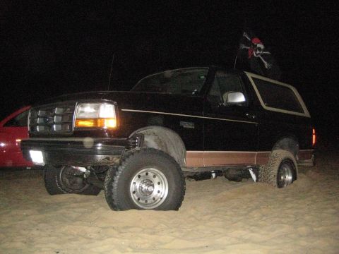 1994 Ford Bronco - This 1994 Ford Bronco, flying a pirate flag, appears to have flat tires while parked on sand.