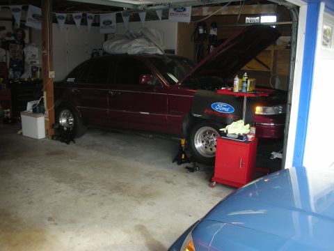 1992 Ford Crown Victoria - A maroon 1992 Ford Crown Victoria is parked in a garage with its hood up, showing the engine bay.