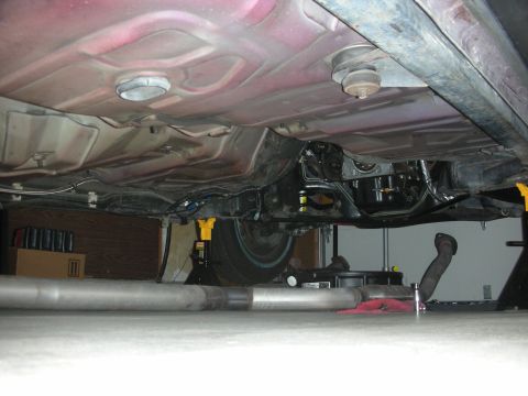 1992 Ford Crown Victoria - Undercarriage view of a vehicle, showing the exhaust system and frame components. The vehicle is supported by jack stands.