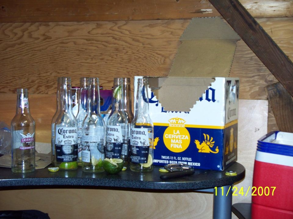 Empty Corona beer bottles and a partial cardboard box on a shelf, with a date stamp of 11/24/2007
