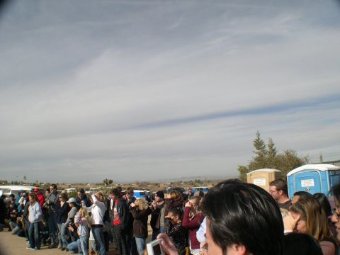 2007 Toyota FJ Cruiser - A group of people are assembled outdoors under a cloudy sky, with portable toilets in the distance.
