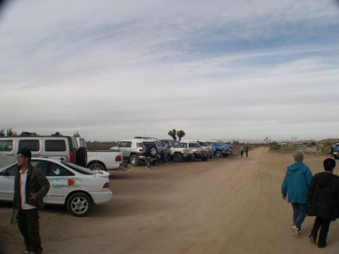2007 Toyota FJ Cruiser - A group of vehicles are parked in a dusty, open area with sparse vegetation under a cloudy sky.