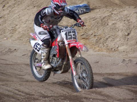 2007 Ford Ranger - A motocross rider navigates a dirt track on a Honda dirt bike, kicking up dust.