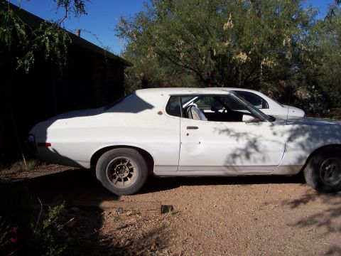 1972 Ford Ranchero - A white 1972 Ford Ranchero coupe is parked next to another vehicle, with a roll cage visible through the window.