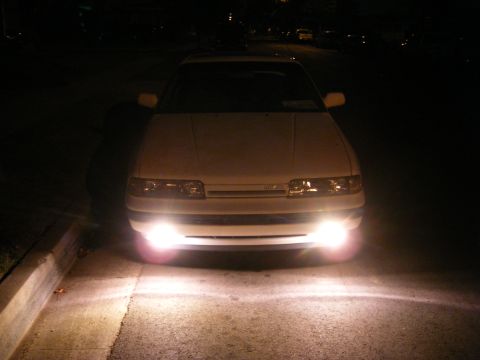 1991 Mazda MX-6 - Front view of a 1991 Mazda MX-6 at night, headlights illuminating the road.
