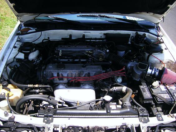 Engine bay with red plug wires and red cone air filter in white car
