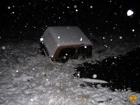 2000 Chevrolet Tahoe - A vehicle is stuck in the snow and water during a nighttime snowfall.