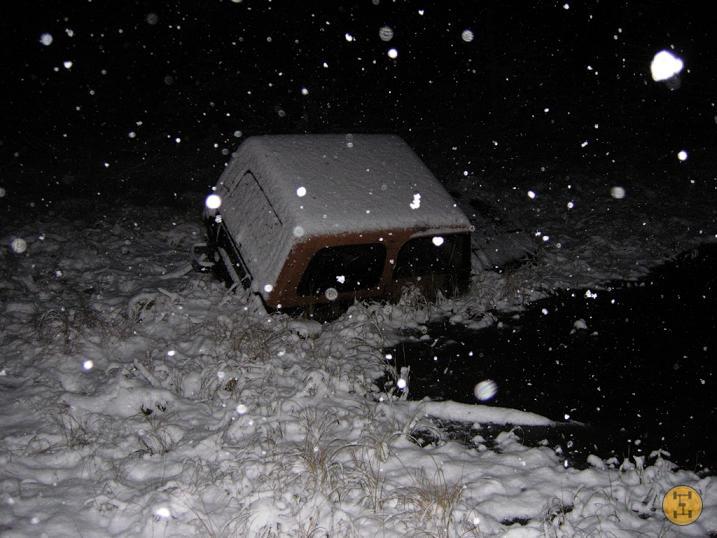Off-road vehicle partially submerged in snow and water at night
