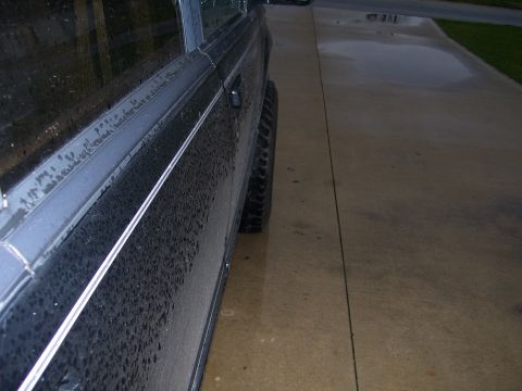 1996 Ford Explorer - Side view of a dark SUV on a wet driveway, showing a white pinstripe along the door.
