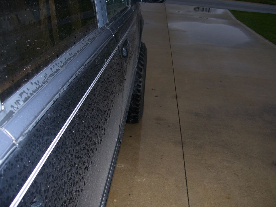 Dark SUV side view, wet surface, white pinstripe on door
