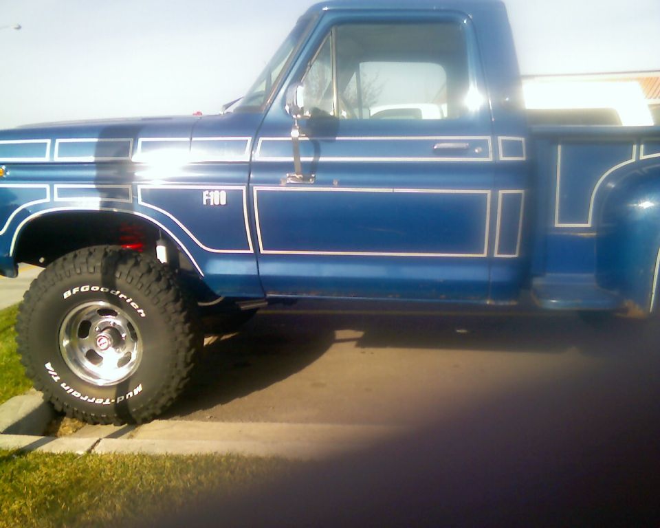 Blue 1970s Ford F-100 stepside pickup with pinstriping on a driveway