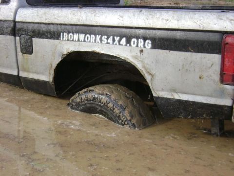 1990 Ford Ranger - Pickup truck is stuck in mud, with visible text on its side.