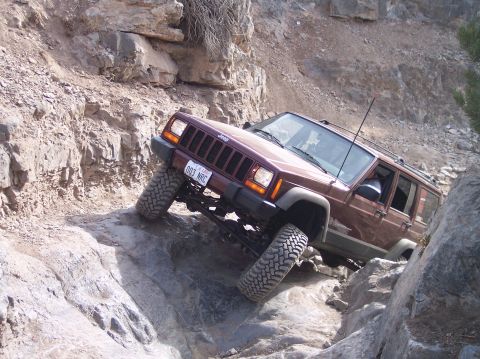 1995 Ford Bronco - Jeep Cherokee XJ tackling a difficult rocky terrain, showing its off-road capabilities.