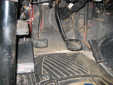 1990 Ford Bronco - Interior view of a vehicle's footwell, displaying pedals and wiring, with an aftermarket module installed.