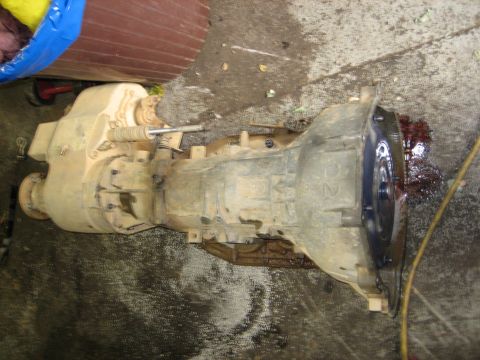 1990 Ford Bronco - Transmission and transfer case assembly shown on a concrete surface, with some fluid leakage visible.