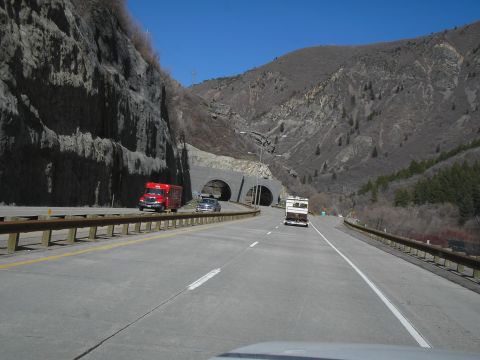 1989 Ford F-250 - A red truck and an RV travel on a highway approaching a tunnel through a rocky mountainside.